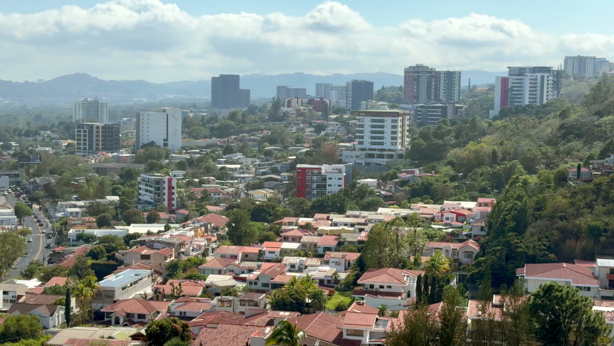 Vista aérea de San Salvador con torres modernas, colonias y las montañas del valle