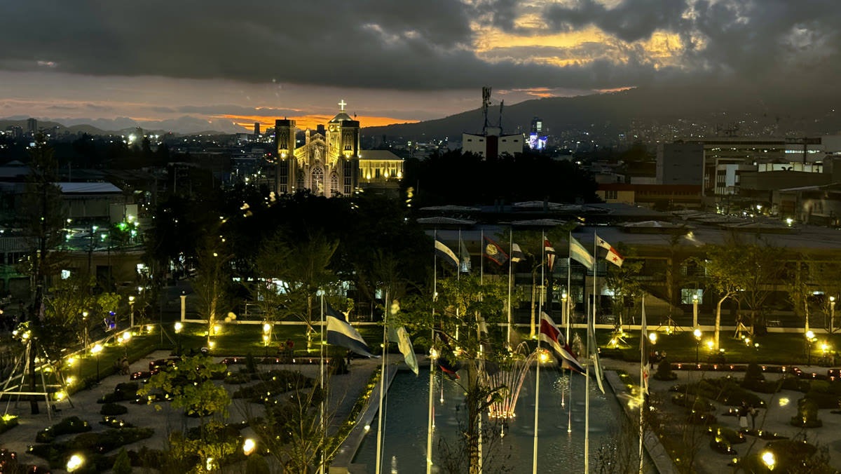 El centro de San Salvador al atardecer, con la iglesia iluminada y el valle de fondo.
